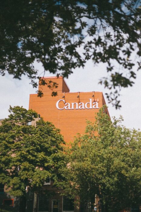 Low angle view of a building with 'Canada' text, surrounded by trees.